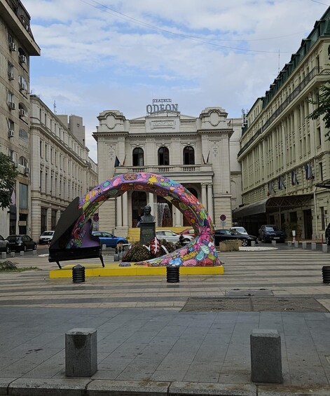 A colorful archway with a piano in front of a classical building. 2