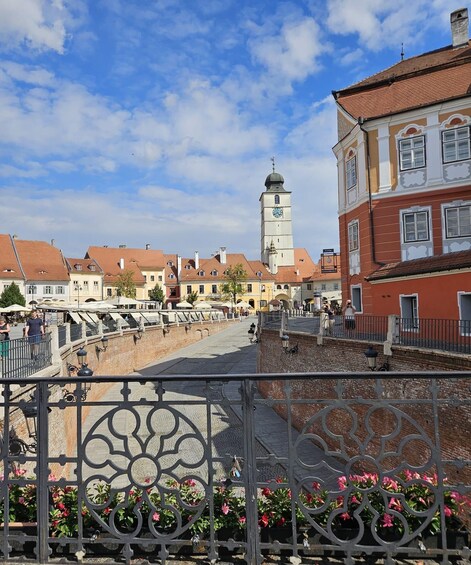 A historic town square with a prominent clock tower, cobblestone streets, and traditional buildings. 5