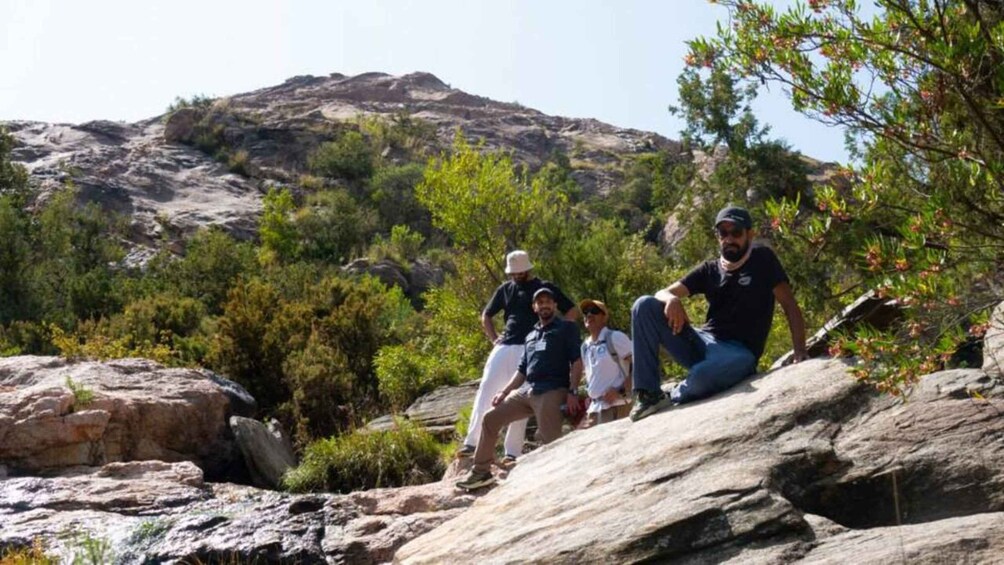 A group of people sitting on rocks with a mountainous landscape in the background. 1