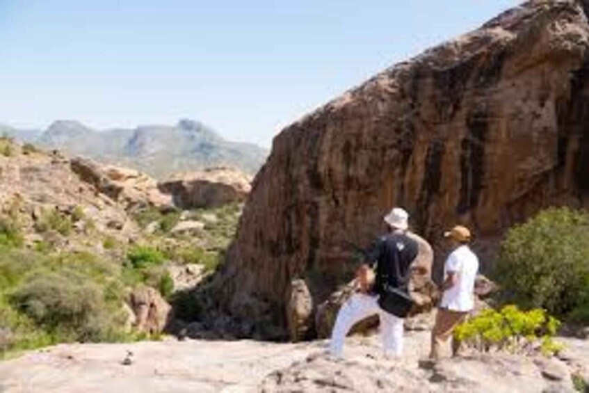 A rocky landscape with a large boulder and a person in white clothing. 2