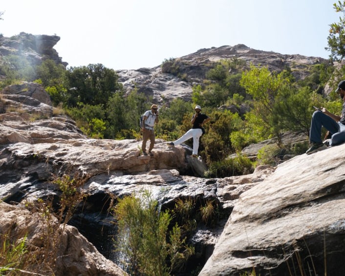 People hiking on rocky terrain with a mountainous backdrop. 3