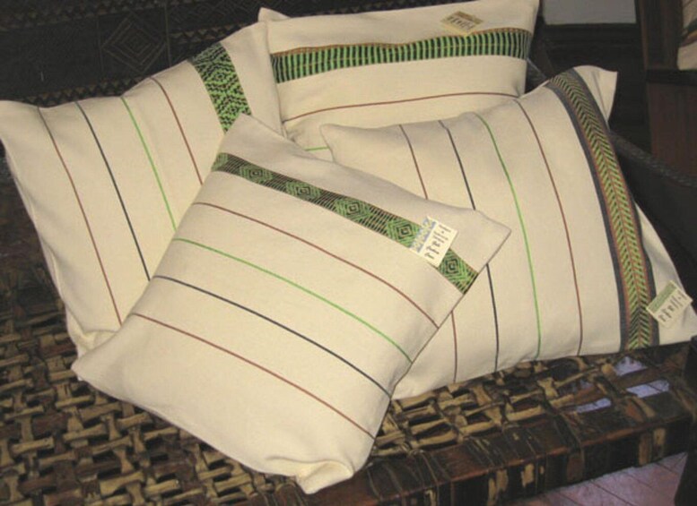 Pillows with striped patterns and green borders on a woven surface. 2