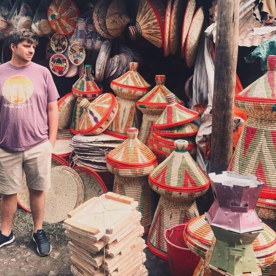 A person standing next to a variety of colorful woven baskets and containers. 4