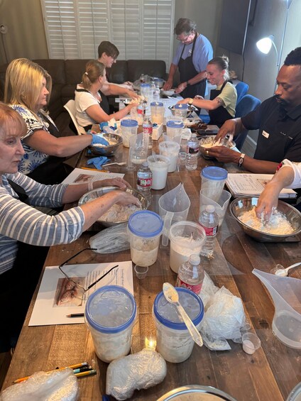 A group of people engaged in a baking activity around a long wooden table filled with ingredients and utensils. 5