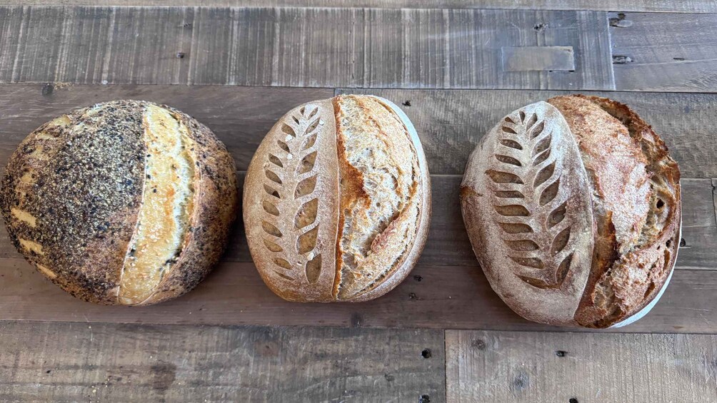 Three loaves of artisan bread on a wooden surface. 4
