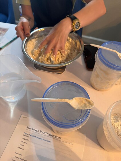 A person mixing ingredients in a bowl, with a recipe card visible on the table. 3