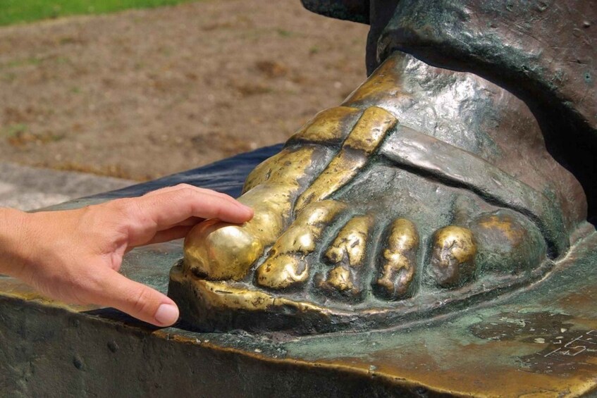 A bronze sculpture of a hand touching a textured surface. 5