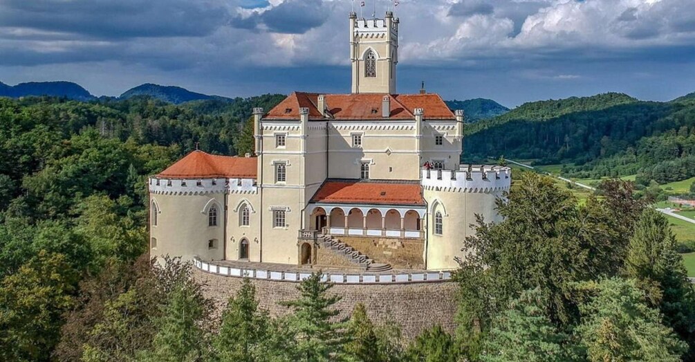 A castle with a central tower, surrounded by a moat and set in a forested valley. 1