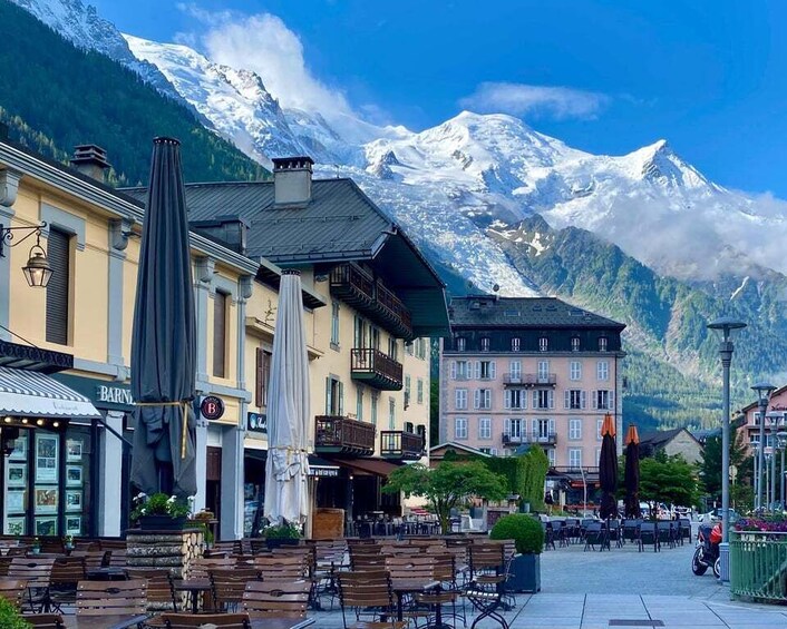 A mountain town with snow-capped peaks, outdoor seating, and historic buildings. 3