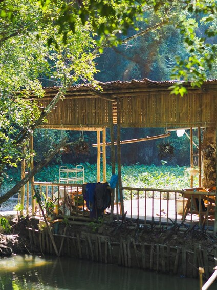 A bamboo structure by a water body, surrounded by lush greenery. 1