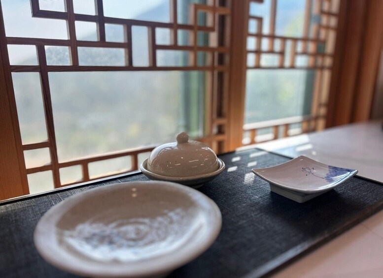 A traditional tea set on a tray by a window with a wooden lattice. 2