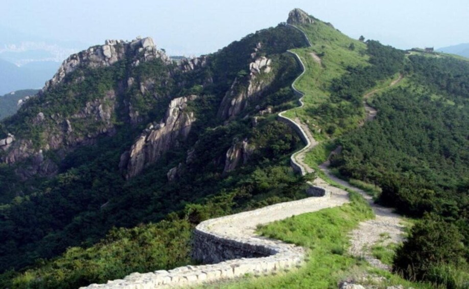 A winding mountain road surrounded by lush greenery and rocky cliffs. 3