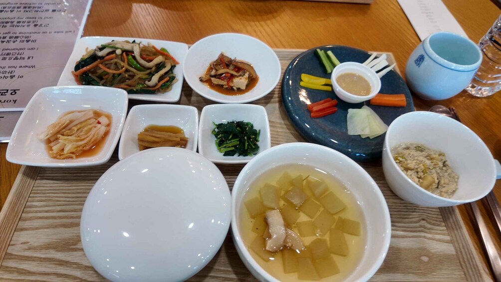 A variety of dishes including a bowl of soup, a plate with vegetables, and several small dishes with different sauces. 1