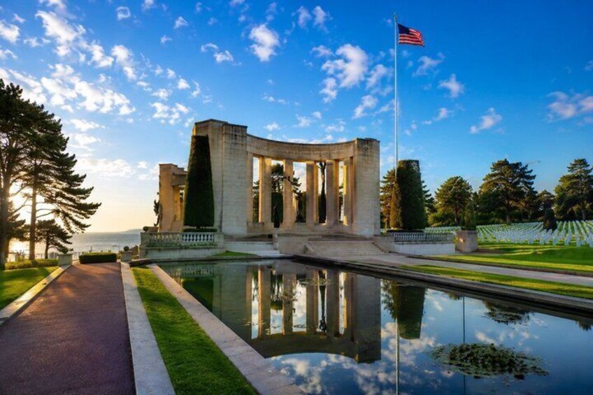 A memorial with columns, a flag, and a reflective pool. 1