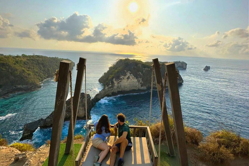 A couple sitting on a swing overlooking a coastal landscape with cliffs and the ocean. 4