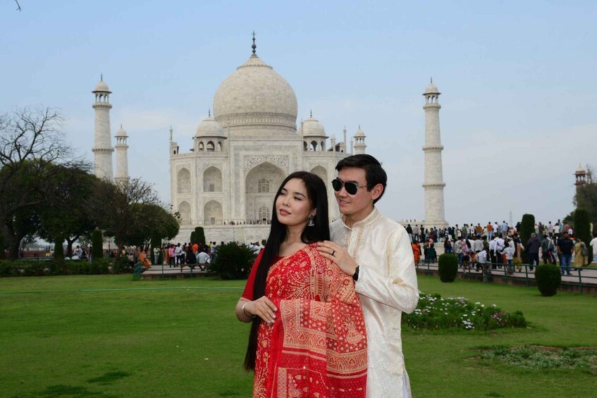 A couple in traditional attire standing in front of the Taj Mahal. 4