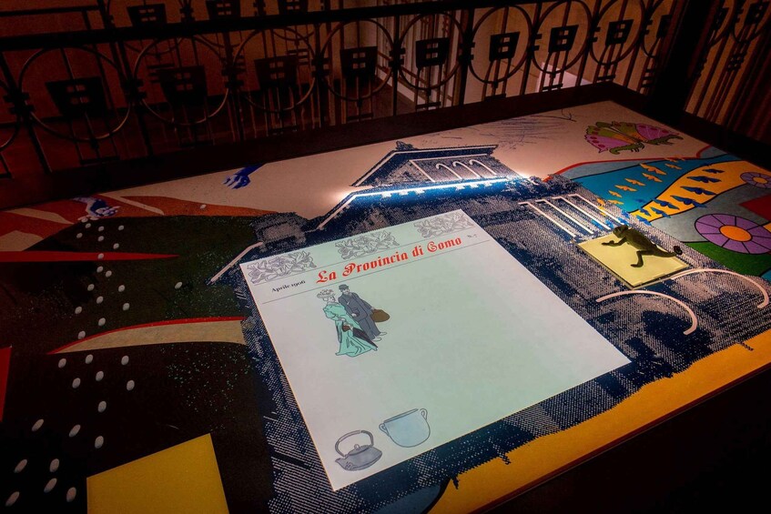 A table with a colorful tablecloth, a drawing of a building, and a piece of paper with text and a drawing of a person. 2