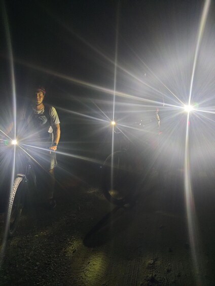 A person standing in a dark environment with multiple light sources creating starburst effects. 5