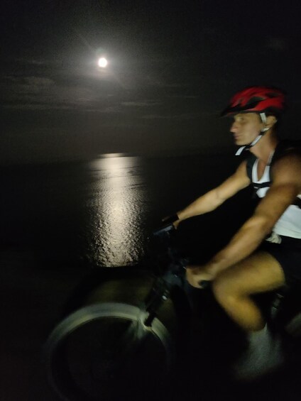 A person riding a bicycle at night with a bright light source in the background. 2