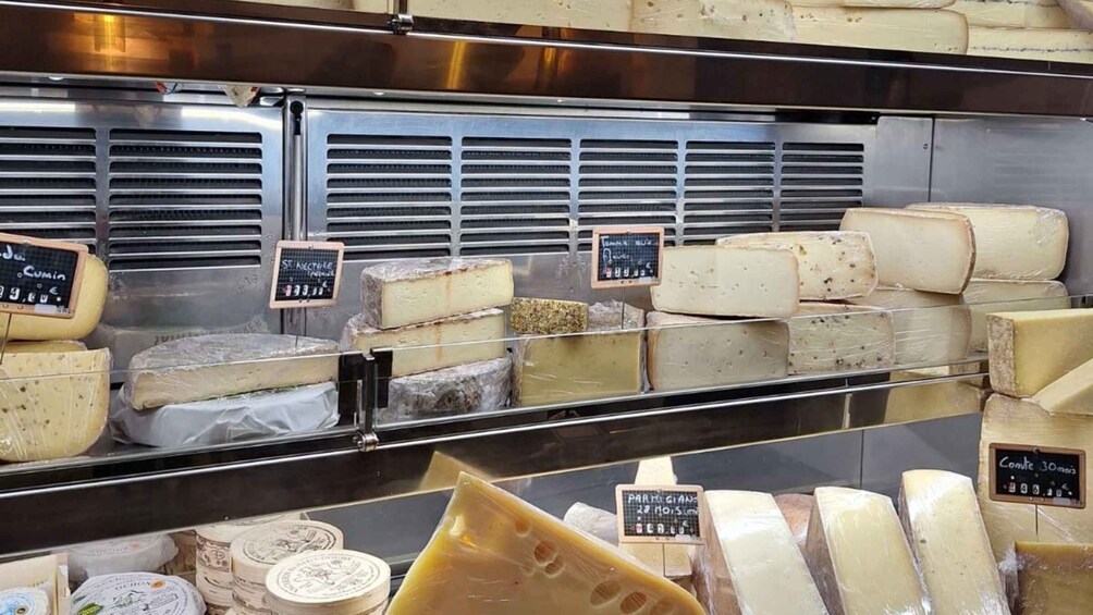 A cheese display with various types of cheese in a refrigerated case. 2