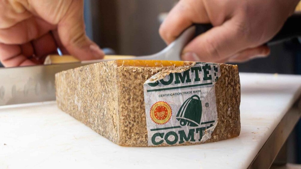 A person cutting a block of cheese with a knife. 4