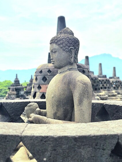 A stone Buddha statue in a temple setting with traditional architecture in the background. 3