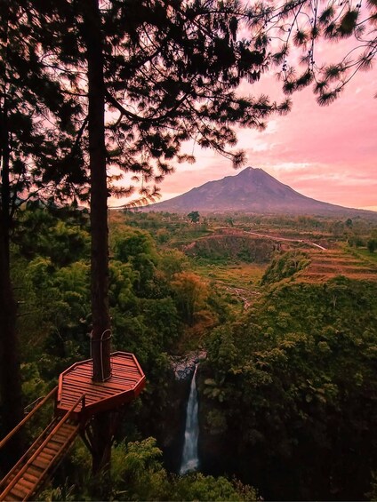 A wooden viewing platform overlooking a waterfall and a mountain in the distance. 1