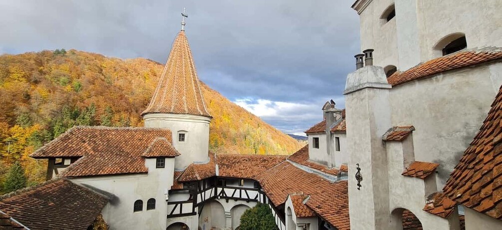 A historic town with a prominent church tower, traditional buildings, and a hillside in autumn. 1