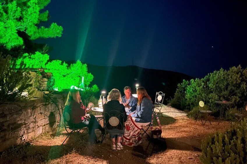 A group of people sitting at a table outdoors at night, illuminated by artificial light. 2