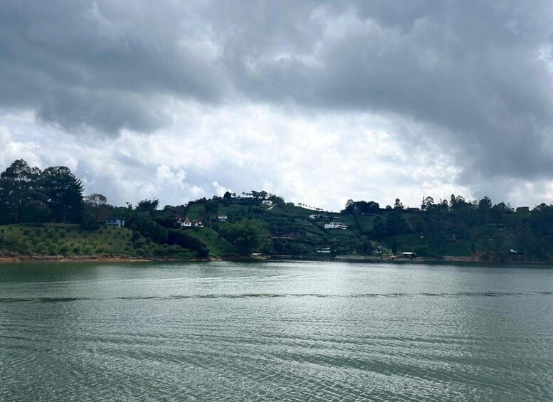 A lake with calm water, surrounded by hills with scattered houses. 4