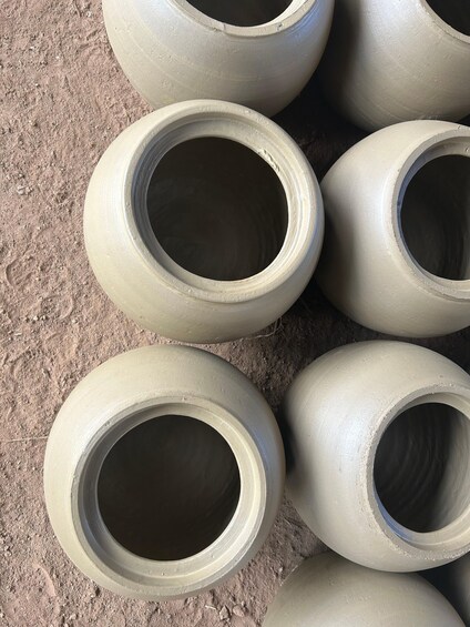 Several large, cylindrical concrete pipes stacked on a dirt ground. 1