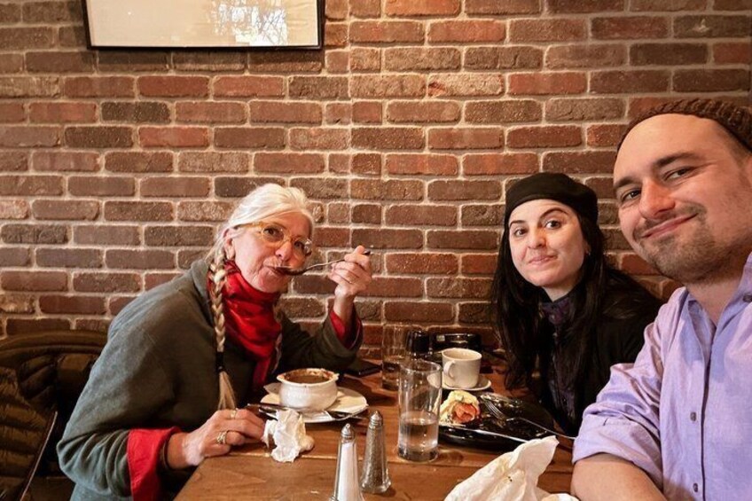 Three people dining at a table with a brick wall background. 1