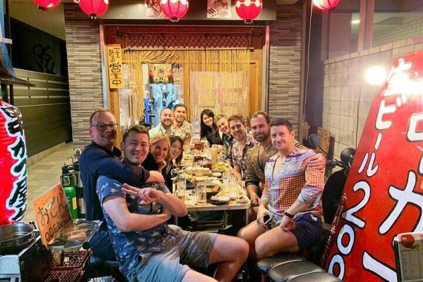 A group of people seated around a table with food, in a restaurant with Asian decor and red lanterns. 5