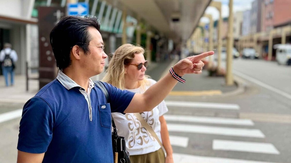 A man pointing towards a crosswalk on a city street. 4