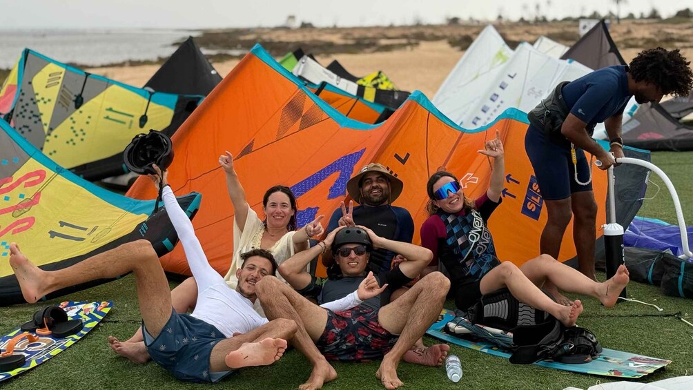 A group of people on a grassy area with colorful kites and a beach in the background. 5