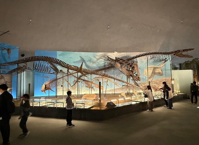 A museum exhibit with large dinosaur skeletons and a desert landscape backdrop. 4