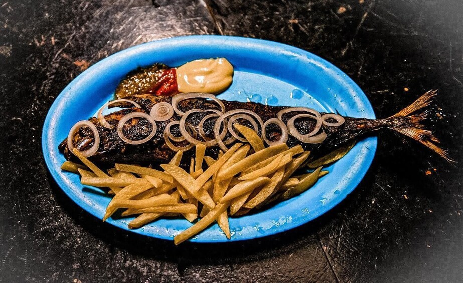 A fish on a blue plate with fries and a sauce. 3