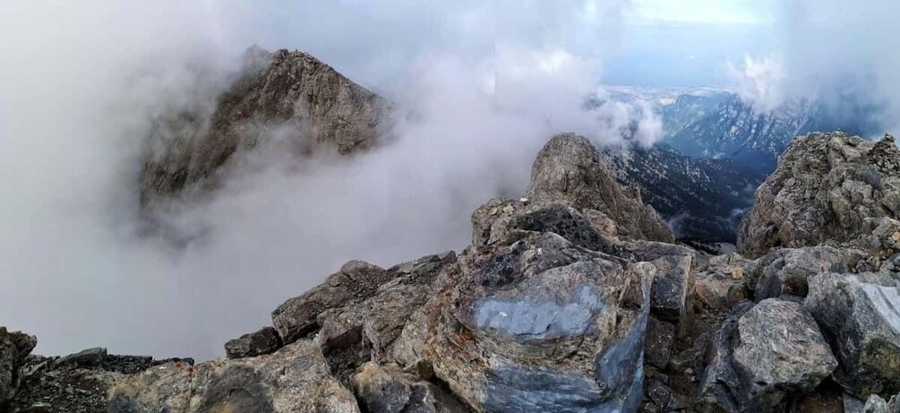 A rugged mountain peak with rocky terrain and clouds at the summit. 3