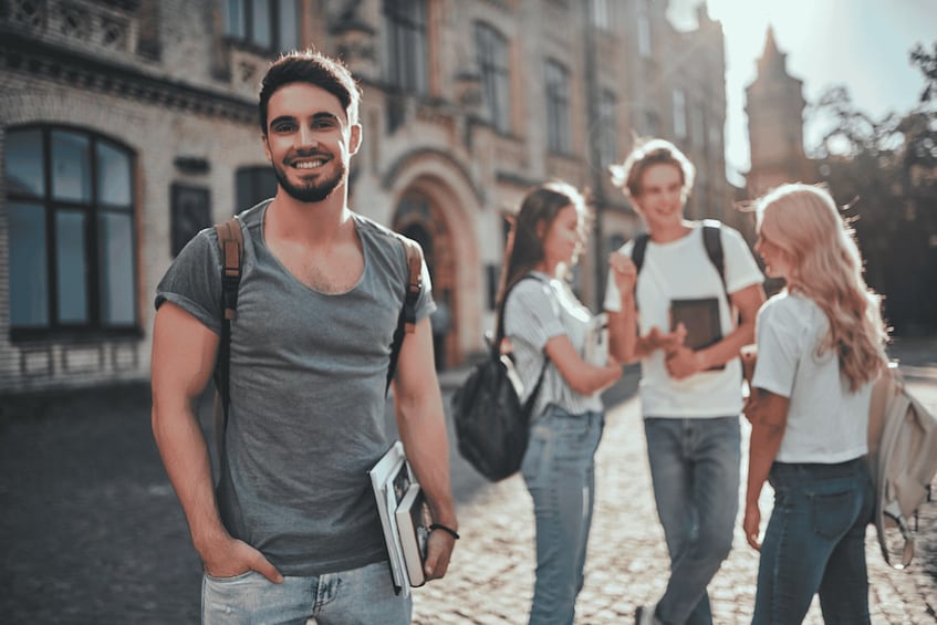 A cobblestone street with historic buildings, a person with a backpack, and two people conversing. 1