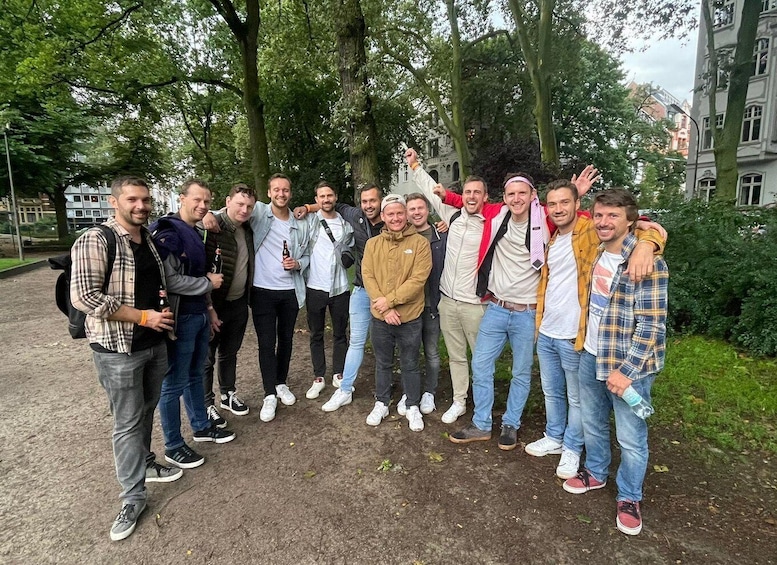 A group of people standing outdoors with trees and buildings in the background. 2