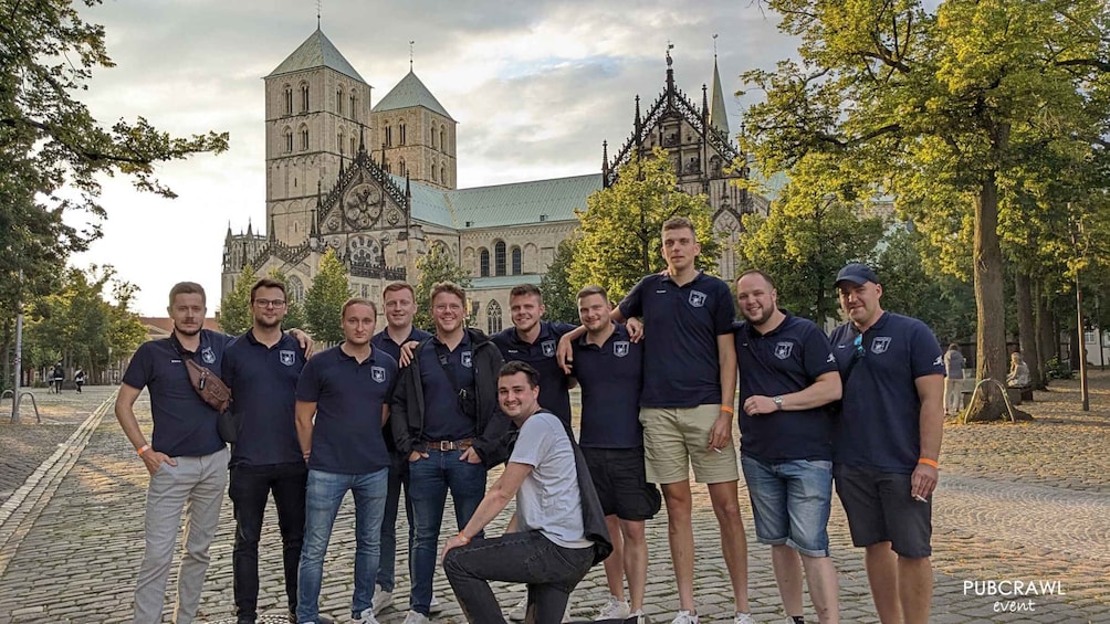 A group of people in matching shirts standing in front of a historic building with towers and a spire. 3