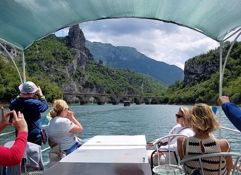 A boat tour with passengers taking photos of a bridge over water. 3