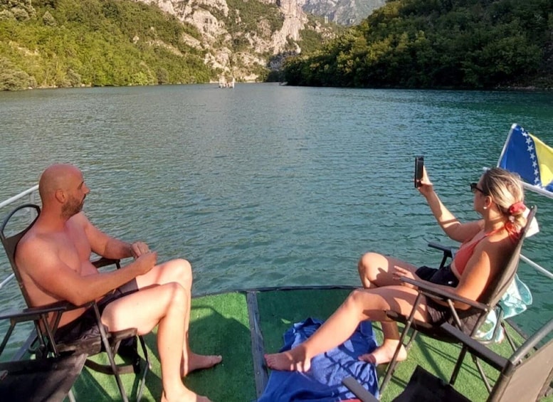 Two people on a boat in a lake with mountains in the background. 1