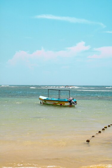 A boat anchored near the shore with clear water and a calm sea. 3