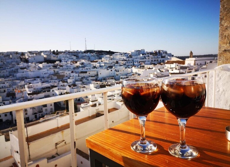 Two glasses of red wine on a balcony overlooking a white-washed town. 3