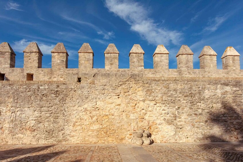 A stone wall with crenellations and a clear blue sky. 2
