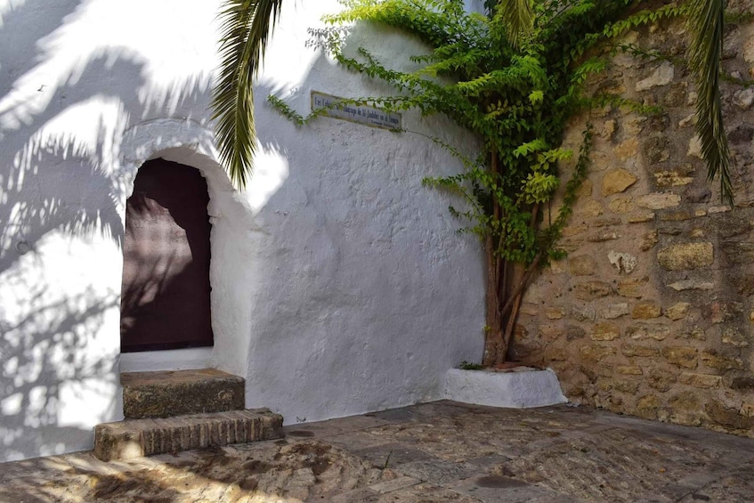 A white wall with a stone door, steps leading up to it, and a sign with text. 1