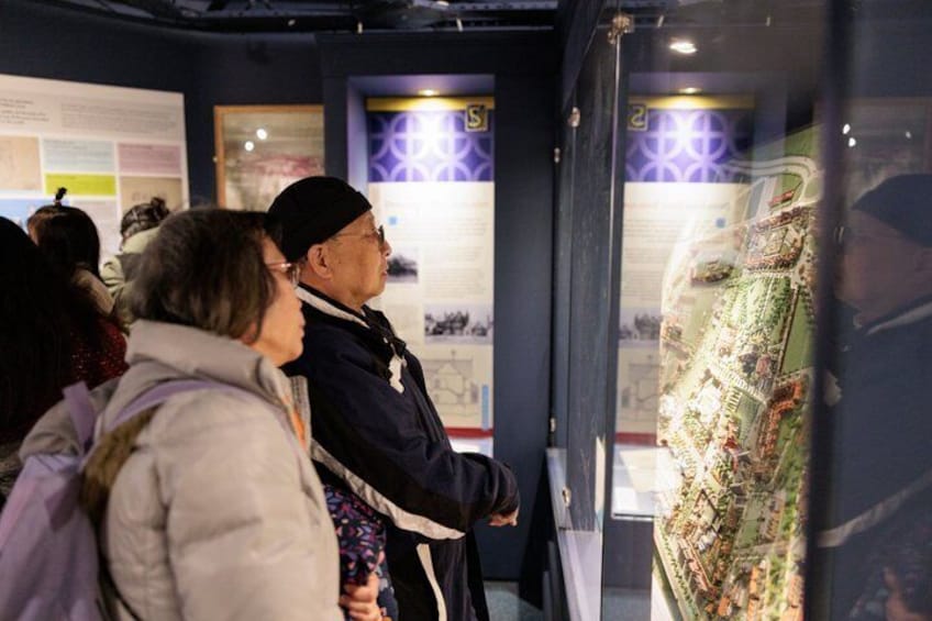 People observing a museum exhibit with informational panels and a detailed map. 3