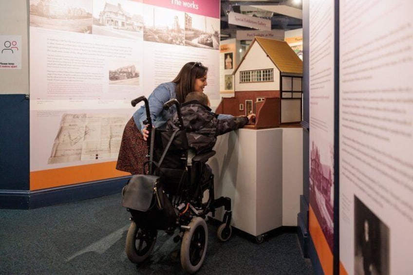 A person in a wheelchair examining a model house at an exhibition. 4