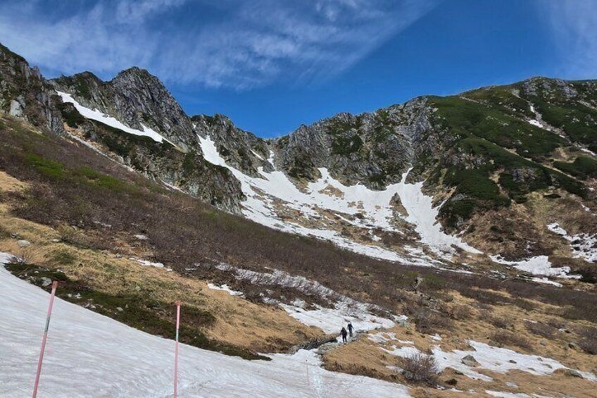 A mountainous landscape with snow patches and a clear sky. 3